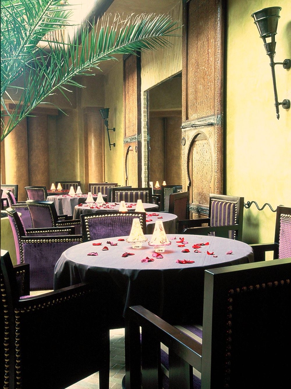 The dining room of La Maison de Charly, palm tree and carved Moroccan door