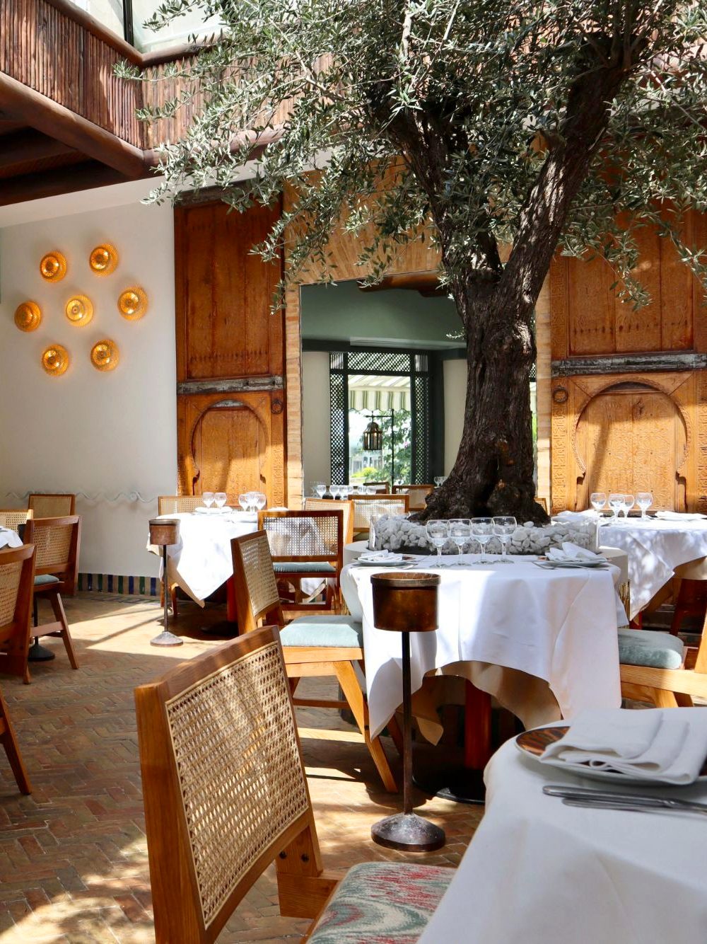 The Charly dining room today, its olive tree and golden wall lamps